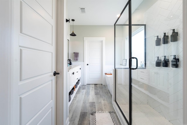 bathroom with visible vents, wood finished floors, a stall shower, and vanity