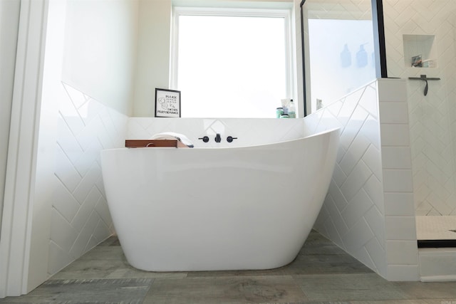 bathroom featuring tile walls, a freestanding bath, tiled shower, and wood finished floors