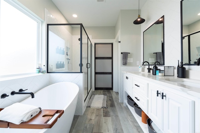 full bathroom featuring a freestanding bath, tile walls, a stall shower, wood finished floors, and a sink
