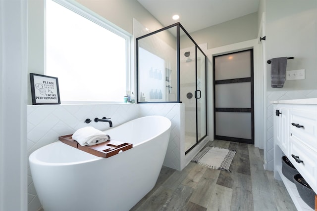 full bath featuring a freestanding bath, tile walls, a stall shower, wood finished floors, and vanity