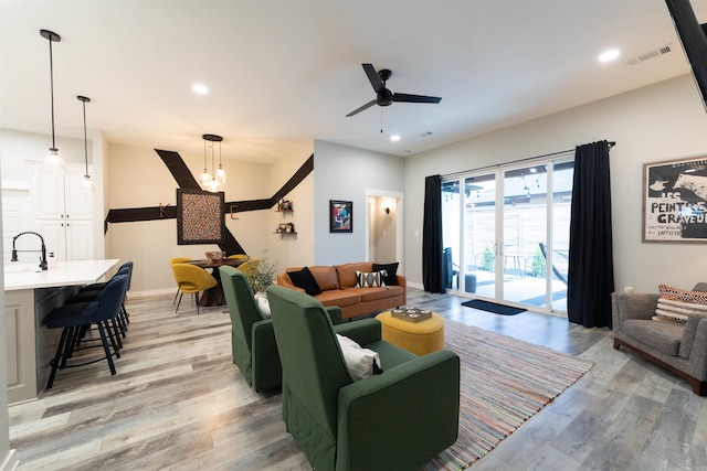 living room featuring light wood-style floors, ceiling fan with notable chandelier, recessed lighting, and visible vents
