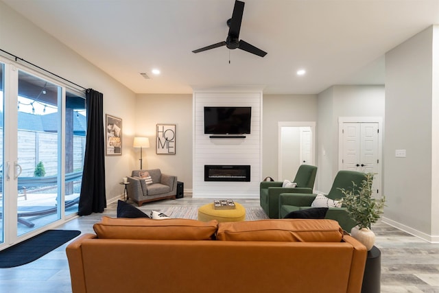 living room featuring a ceiling fan, baseboards, visible vents, and light wood-style flooring