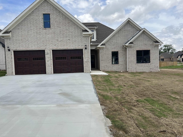 view of front of property featuring concrete driveway, brick siding, an attached garage, and a front yard