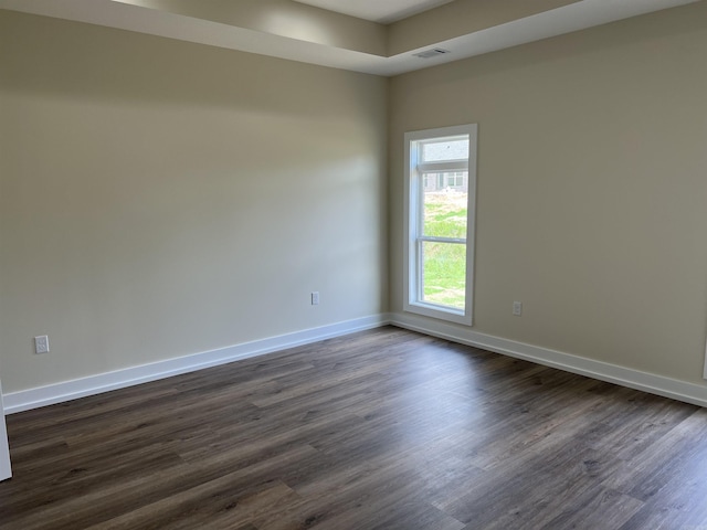 empty room featuring baseboards, visible vents, and dark wood-type flooring