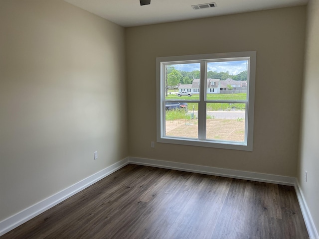 unfurnished room with baseboards, a ceiling fan, dark wood-style flooring, and visible vents