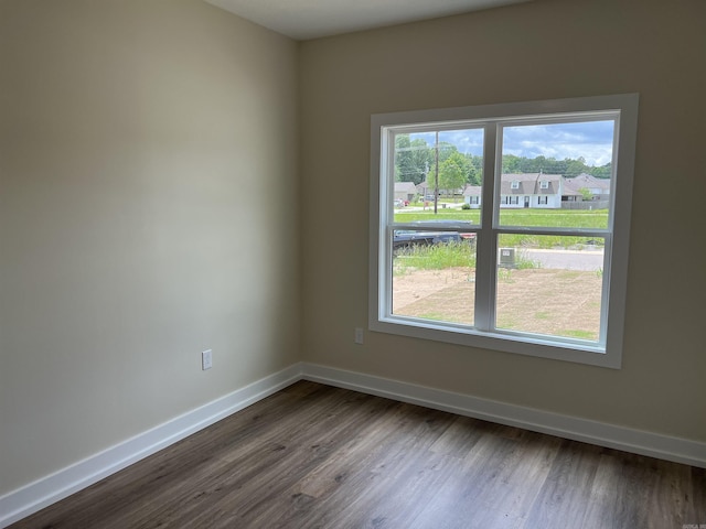 empty room with baseboards, dark wood-style flooring, and a healthy amount of sunlight