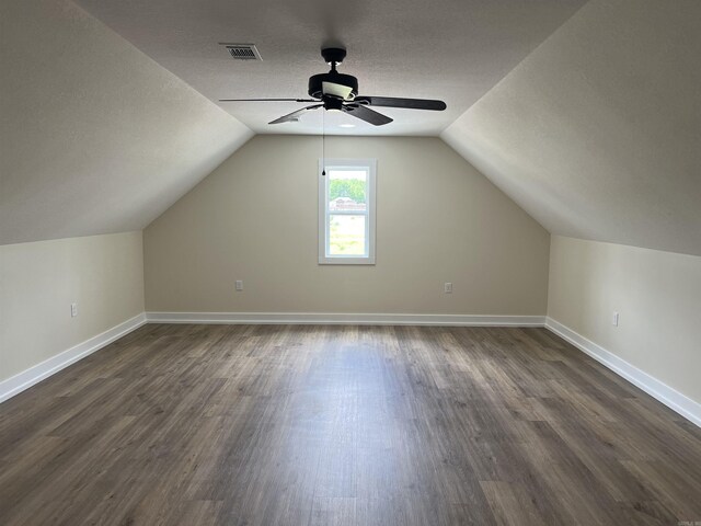 additional living space with baseboards, visible vents, a ceiling fan, and dark wood-type flooring