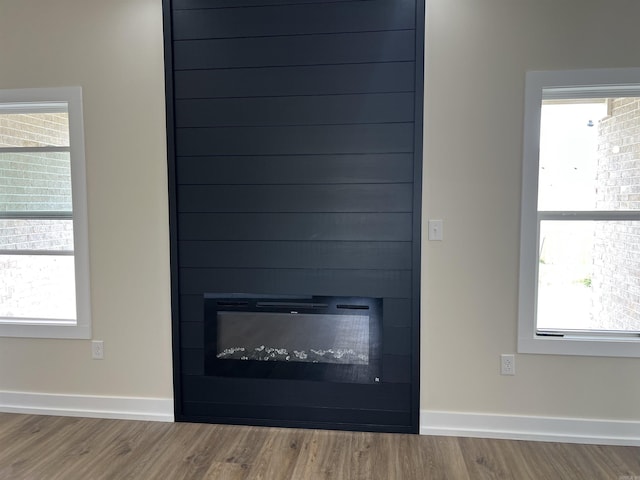 interior details with a large fireplace, baseboards, and wood finished floors