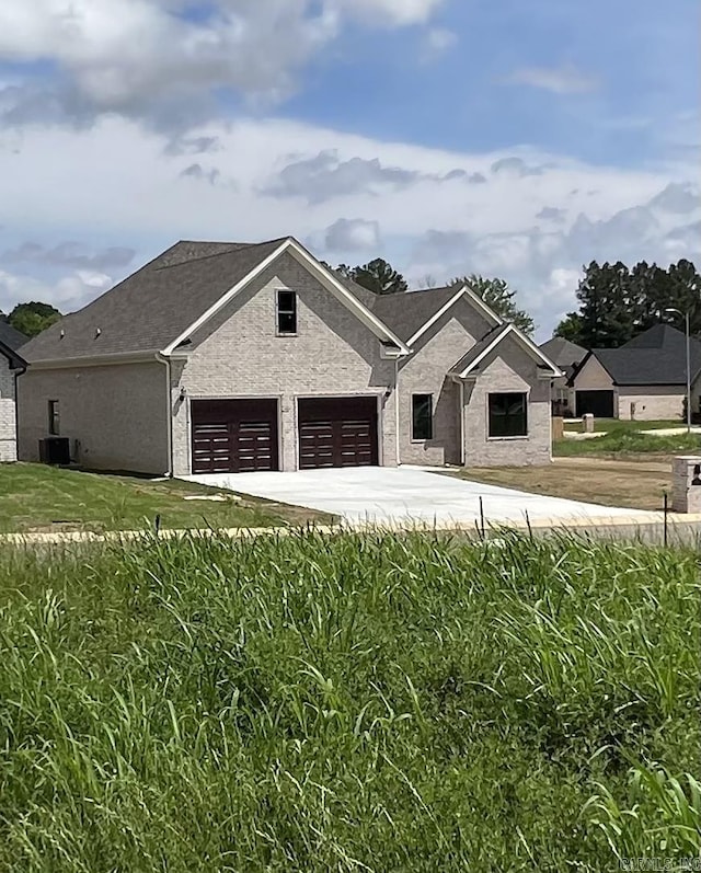 view of front facade with central air condition unit, an attached garage, driveway, and stucco siding