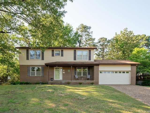 traditional home with covered porch, a front yard, brick siding, an attached garage, and driveway