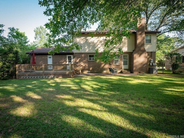 back of property featuring central air condition unit, a lawn, a chimney, and a wooden deck