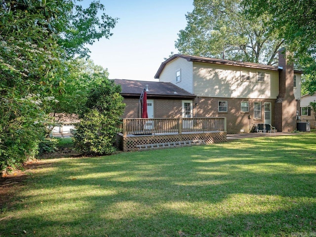 rear view of house with brick siding, a deck, a chimney, cooling unit, and a lawn