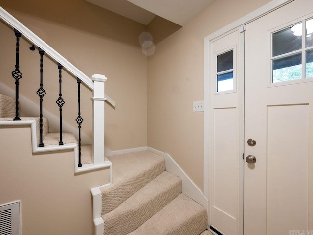 staircase featuring baseboards, carpet flooring, and visible vents
