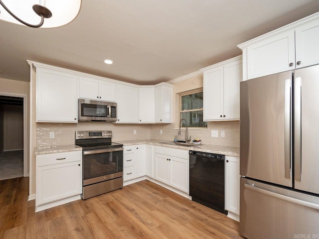 kitchen featuring a sink, white cabinets, light wood finished floors, stainless steel appliances, and recessed lighting