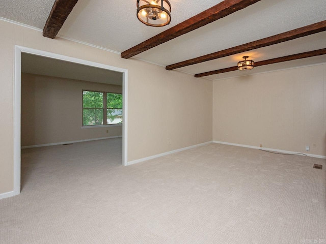 empty room with baseboards, beam ceiling, and light carpet