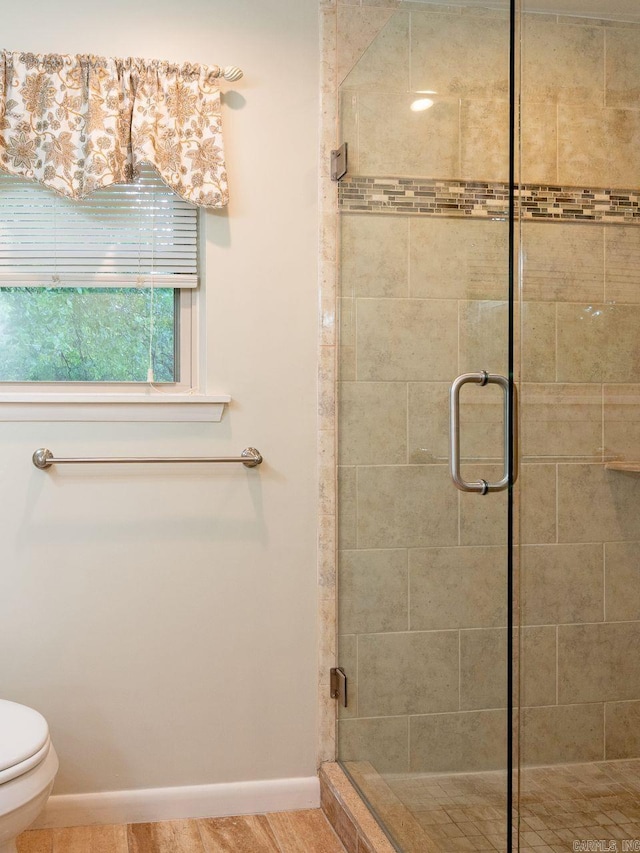 full bathroom featuring baseboards, a shower stall, and toilet