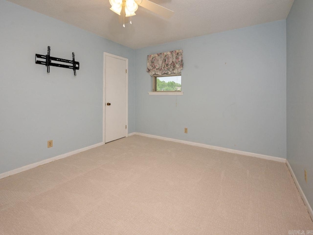 empty room with baseboards, ceiling fan, and light carpet