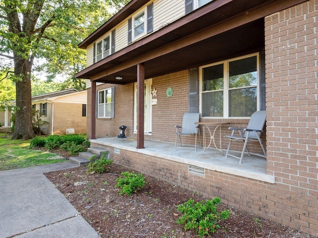 property entrance featuring a porch and brick siding