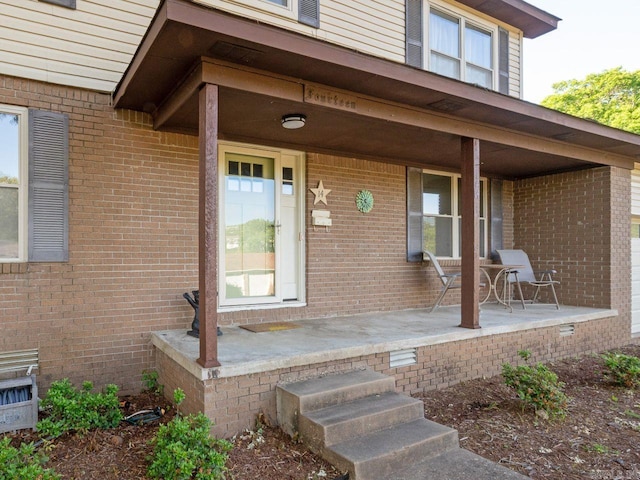 property entrance featuring covered porch and brick siding