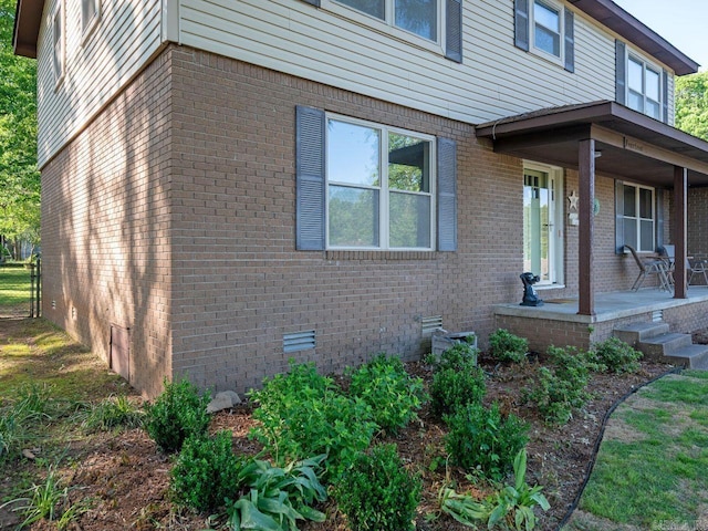 view of side of property featuring covered porch and brick siding