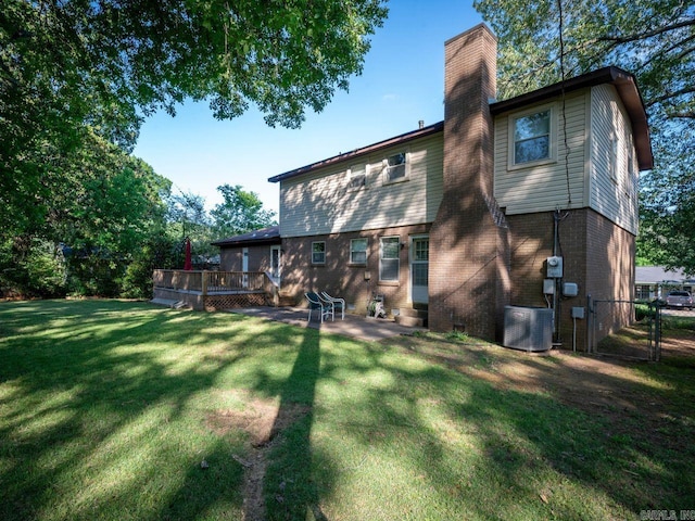 rear view of house featuring a chimney, a lawn, a deck, cooling unit, and fence