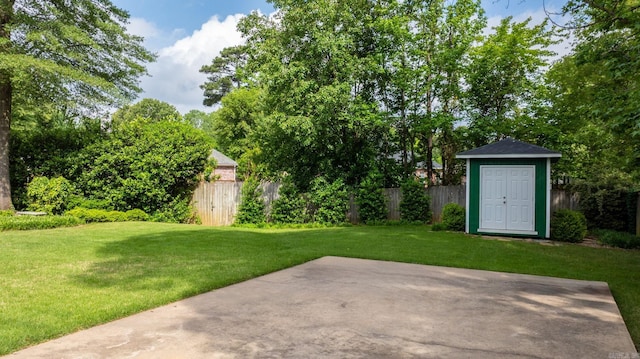 view of yard with a storage shed, a patio area, fence, and an outbuilding