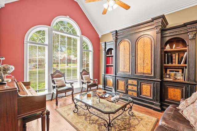 living area with crown molding, high vaulted ceiling, a ceiling fan, and light wood-type flooring
