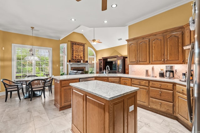 kitchen with brown cabinetry, a kitchen island, a ceiling fan, a fireplace, and a sink
