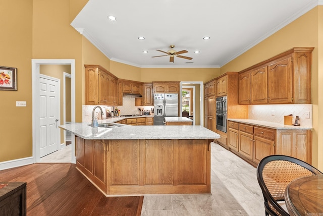 kitchen with ceiling fan, tasteful backsplash, a sink, a peninsula, and stainless steel appliances