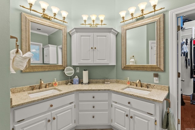 full bath with a sink, ornamental molding, and double vanity