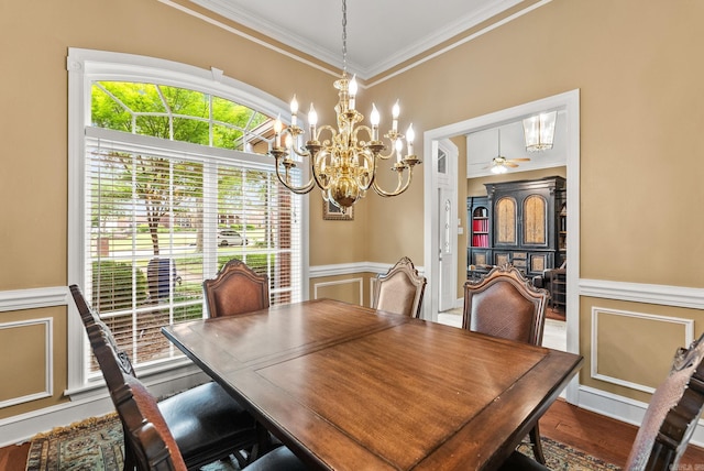 dining room with crown molding, an inviting chandelier, wainscoting, and wood finished floors