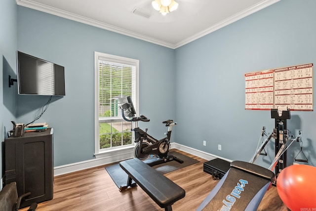 workout room with visible vents, ornamental molding, baseboards, and wood finished floors
