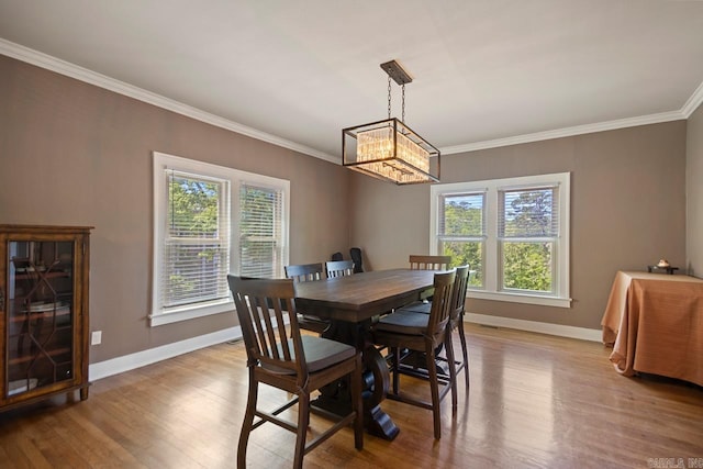 dining area featuring an inviting chandelier, baseboards, crown molding, and wood finished floors