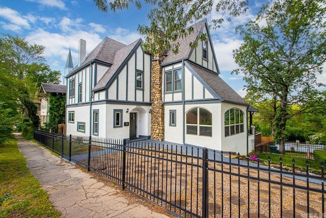 view of front facade with a shingled roof, a fenced front yard, stucco siding, and a chimney