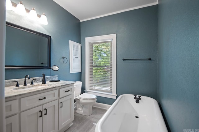 full bathroom with a textured wall, vanity, toilet, baseboards, and a soaking tub