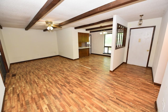 unfurnished living room featuring a ceiling fan, baseboards, beam ceiling, and light wood-type flooring