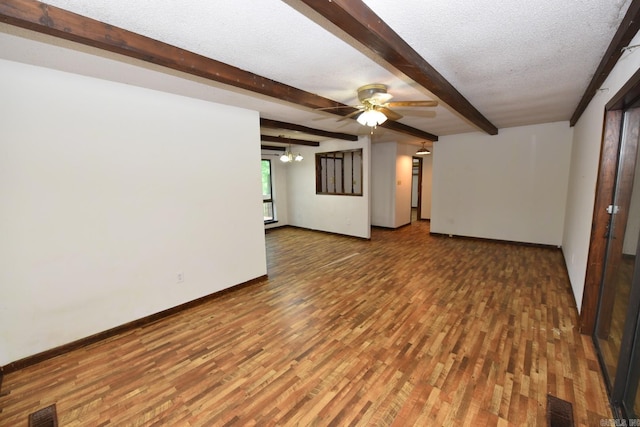 spare room featuring visible vents, wood finished floors, beamed ceiling, baseboards, and a ceiling fan