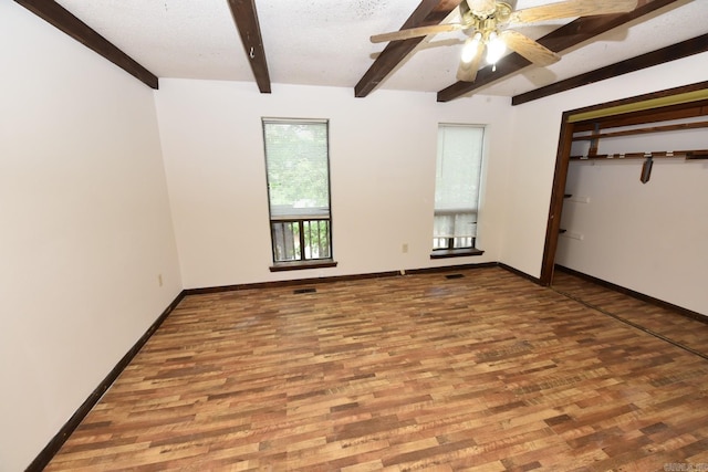 unfurnished room with baseboards, beam ceiling, a ceiling fan, and wood finished floors