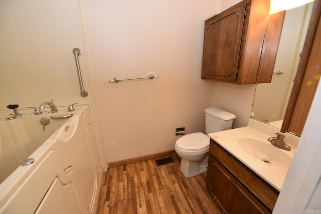 full bathroom with visible vents, wood finished floors, vanity, toilet, and a tub to relax in