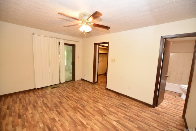 unfurnished bedroom featuring visible vents, baseboards, connected bathroom, a textured ceiling, and light wood-style flooring