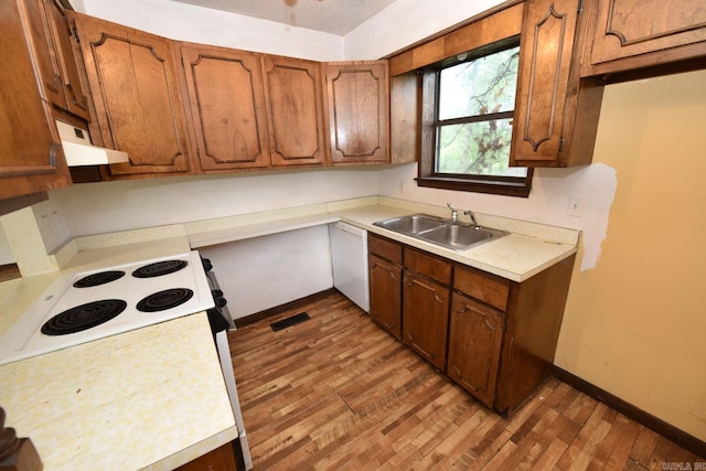 kitchen featuring visible vents, wood finished floors, white dishwasher, under cabinet range hood, and a sink