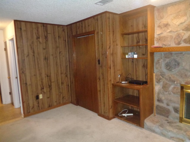 interior space featuring carpet floors, wood walls, a textured ceiling, and visible vents