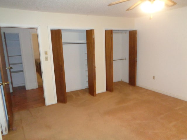 unfurnished bedroom featuring a ceiling fan, two closets, and carpet flooring