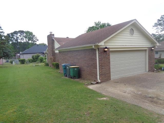 view of side of property featuring a shingled roof, brick siding, a chimney, a lawn, and driveway