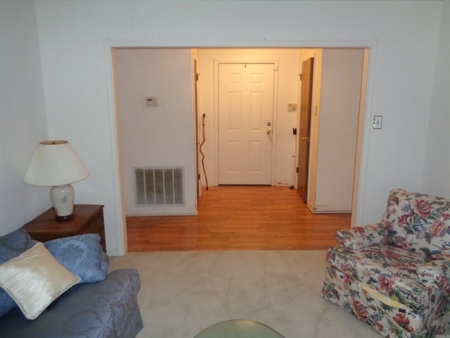 carpeted living room with wood finished floors and visible vents