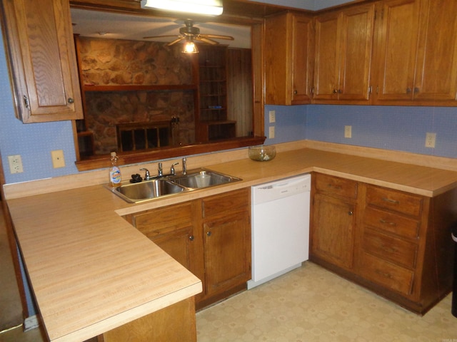 kitchen featuring brown cabinetry, a peninsula, white dishwasher, ceiling fan, and a sink