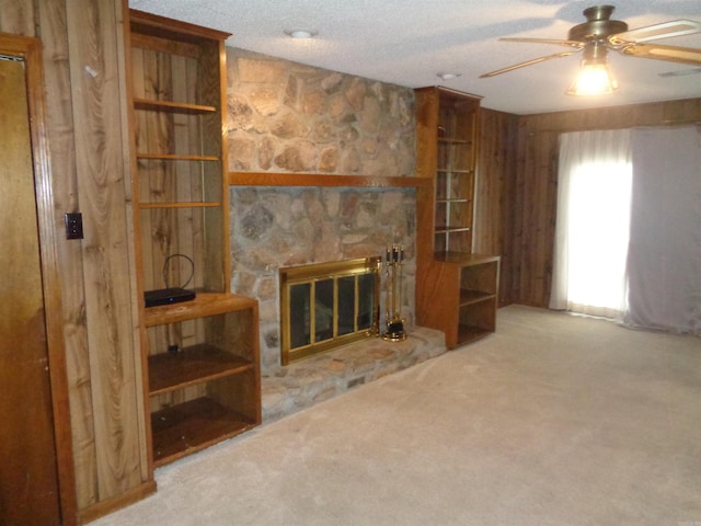 unfurnished living room featuring carpet floors, a fireplace, a ceiling fan, and a textured ceiling