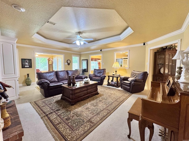 living room featuring ceiling fan, light colored carpet, a raised ceiling, a textured ceiling, and visible vents
