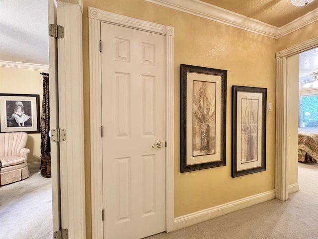 corridor featuring carpet floors, ornamental molding, baseboards, and a textured ceiling