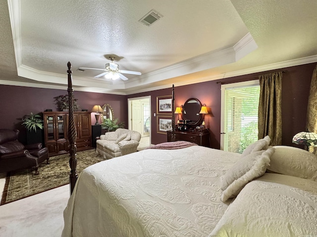 carpeted bedroom featuring crown molding, ceiling fan, a textured ceiling, a tray ceiling, and visible vents